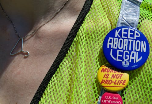 A woman wearing a neon green vest with badge reading: 'Keep abortion legal.'