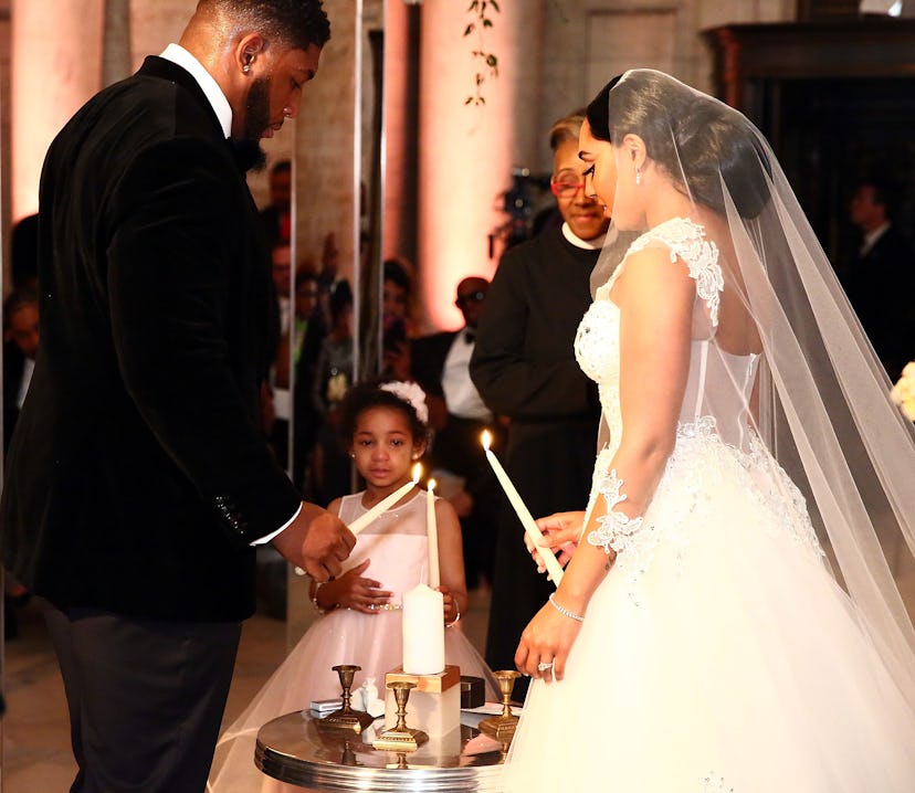 Bride and groom with their child lighting a family unity candle
