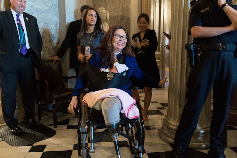 The senator Tammy Duckworth sitting in a wheelchair while holding her newborn baby