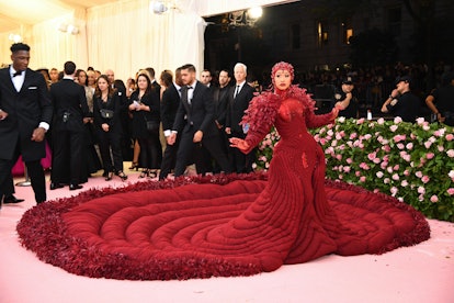 Cardi B at the Met Gala in an oxblood gem-encrusted gown with red leaves and a matching head piece