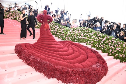 Cardi B at the Met Gala in an oxblood gem-encrusted gown with red leaves and a matching head piece f...