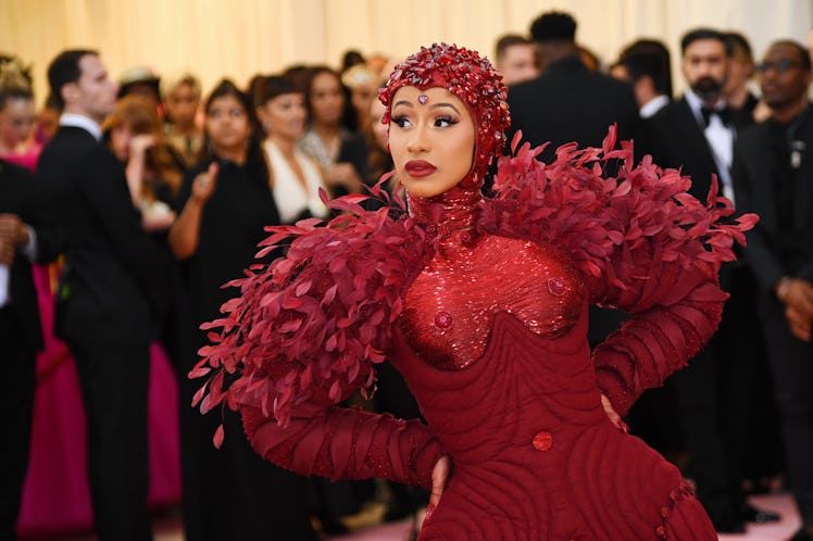 Cardi B at the Met Gala in an oxblood gem-encrusted gown with red leaves and a matching head piece