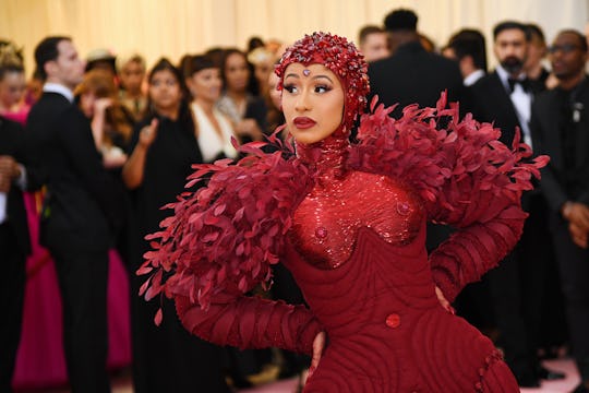 Cardi B at the Met Gala in an oxblood gem-encrusted gown with red leaves and a matching head piece