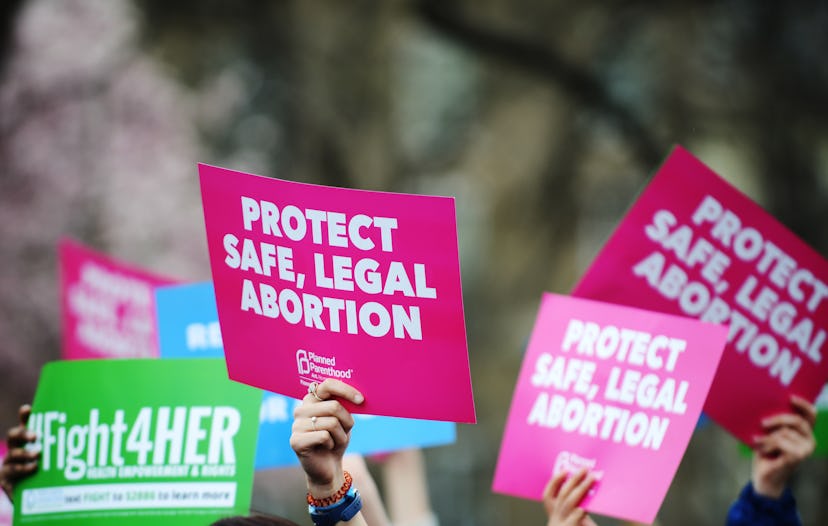 People protesting abortion bans holding signs reading: 'Protect safe, legal abortion.'