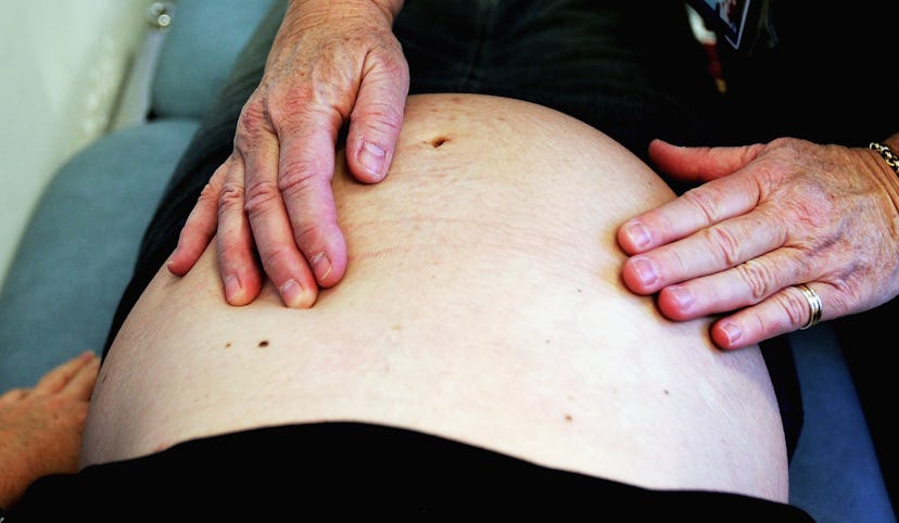 A doctor holding his hands over a woman's pregnant stomach during a check-up