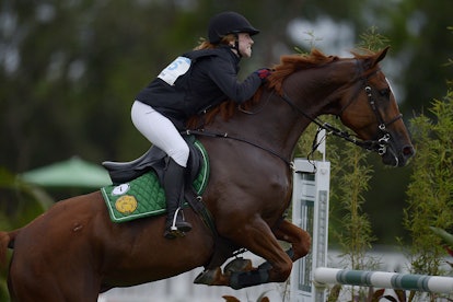 A girl riding a horse over hurdles