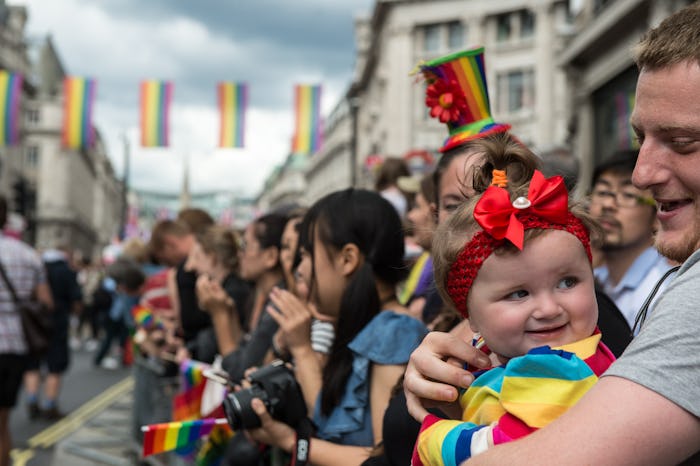 A man holding his child in a crowd while attending a pride event