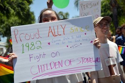 A woman holding a sign that says proud ally since 1982 while at a pride event