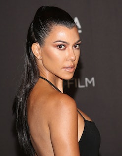 Kourtney Kardashian with a high ponytail in a black dress, posing at an event