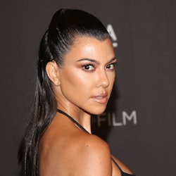 Kourtney Kardashian with a high ponytail in a black dress, posing at an event