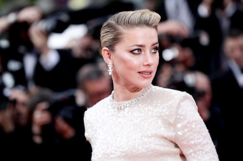 Amber Heard in a glittery white dress, combed over hair at a red carpet event
