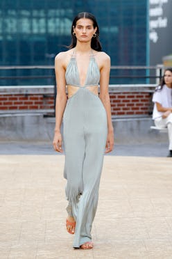 A model walking the runway for Jonathan Simkhai in a grey jumpsuit with reusable nipple covers under...