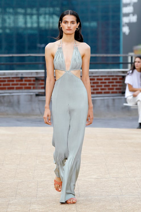 A model walking the runway for Jonathan Simkhai in a grey jumpsuit with reusable nipple covers under...