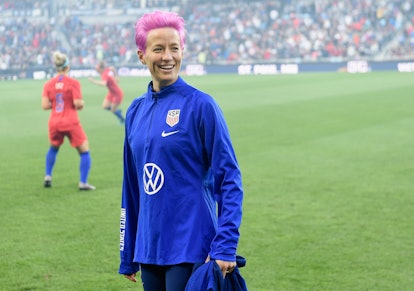 Megan Rapinoe with a pink short haircut on a soccer field