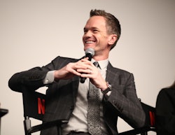 Neil Patrick Harris smiling in a grey suit while giving a speech