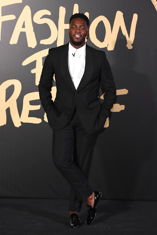 Mo Gilligan at a red carpet in a black suit and white button-up