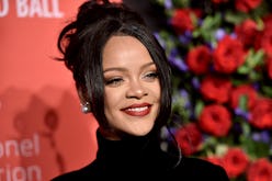 A closeup of Rihanna smiling with her bangs parted to each side of her face