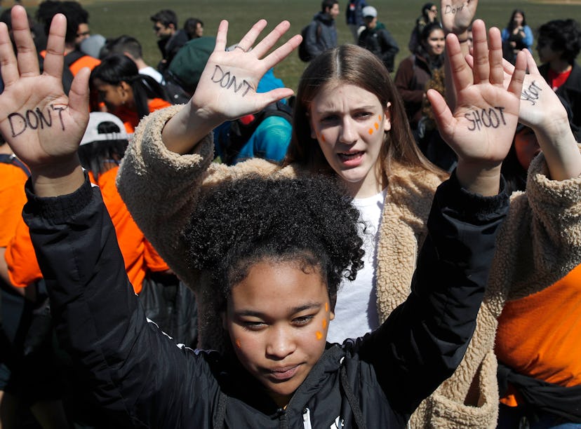 Two girls holding their hands up on protests with "don't shoot" texts on their palms