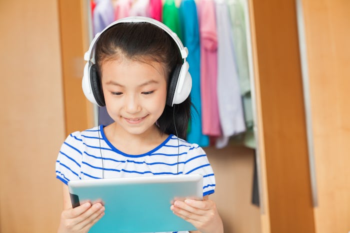 a little girl with headphones listening to audiobook and reading along