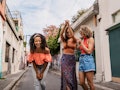 Three friends laugh and dance in the street of a colorful city while on vacation. 