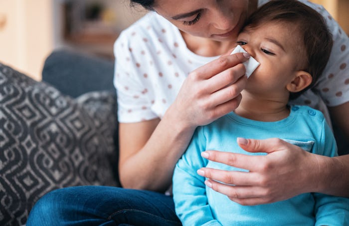 a mom helping little boy blow nose