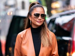 Chrissy Teigen hits the streets in a brown leather jacket.
