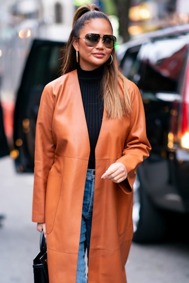 Chrissy Teigen hits the streets in a brown leather jacket.