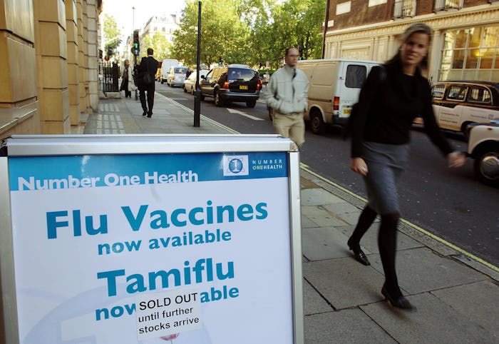 a sign for flu vaccines and Tamiflu on a city sidewalk