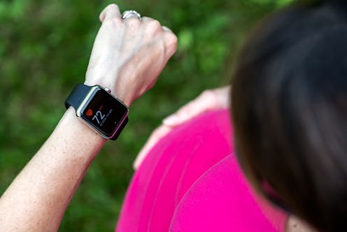 A user wearing a pink shirt checks her Apple Watch. Apple Watch Connected is a new fitness incentive...