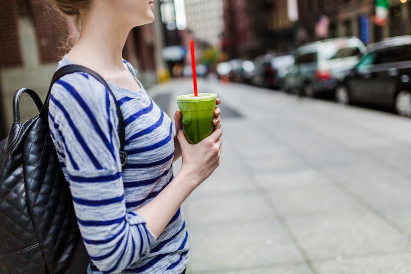 A woman holds a green smoothie. Not drinking alcohol has the unexpected benefit of making you want t...