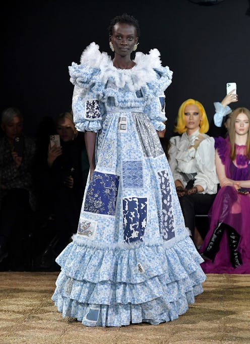 A woman posing in a white and blue couture gown