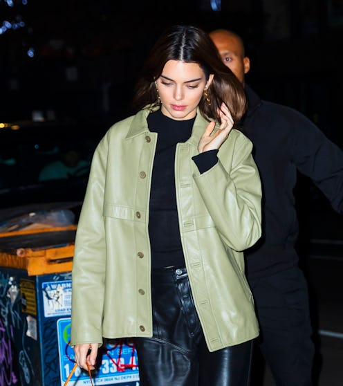 Kendall Jenner walking down the street with her hair down, wearing a light green leather jacket