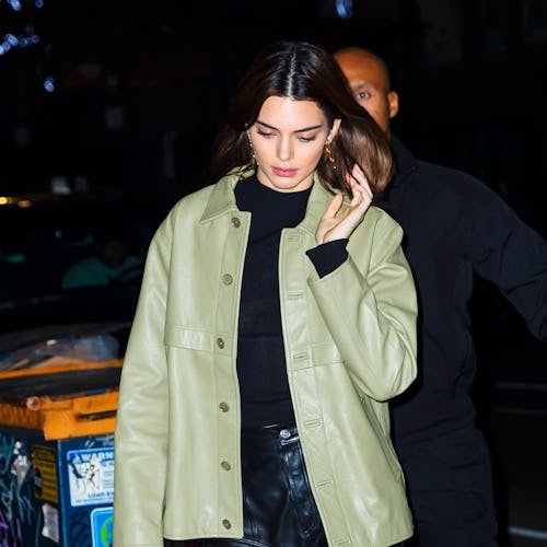 Kendall Jenner walking down the street with her hair down, wearing a light green leather jacket