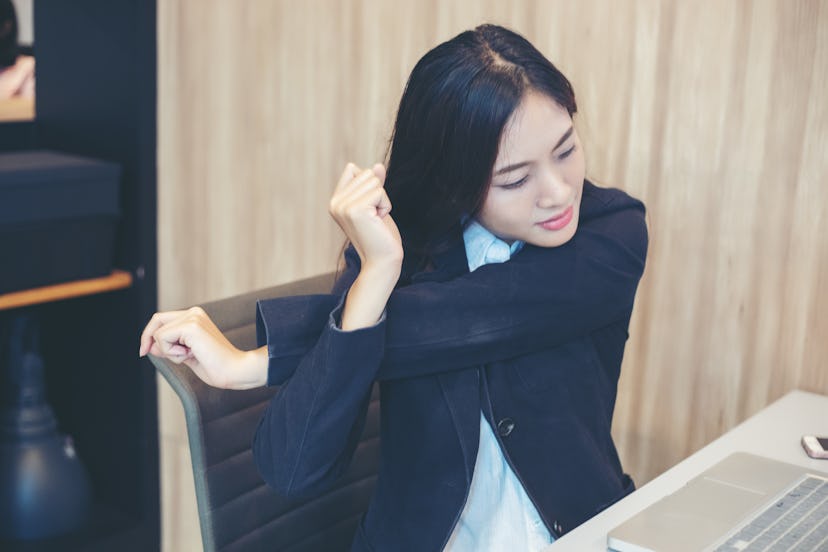 A person stretches her shoulders while sitting at her desk. There are a lot of stretches you can do ...