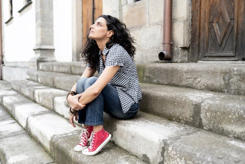 A girl with a trauma sitting alone on outdoor stairs