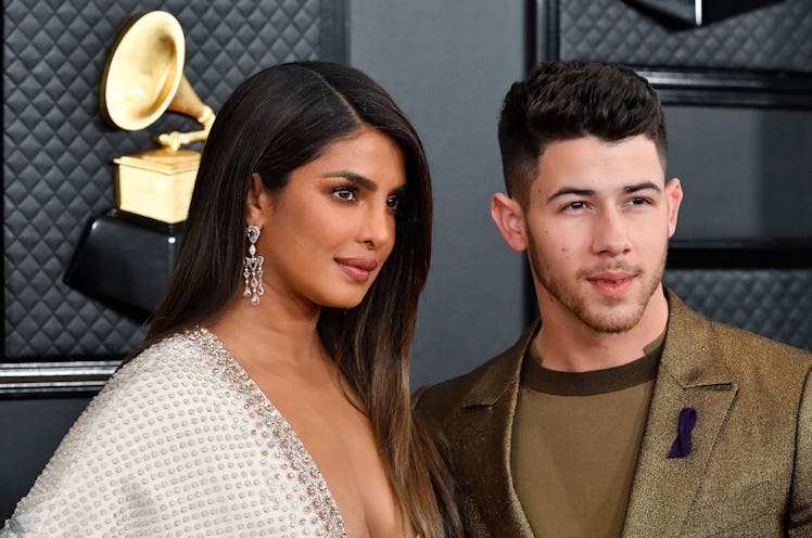 Priyanka Chopra wears a white embellished gown and stands next to husband Nick Jonas on the 2020 Gra...