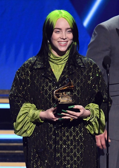 Billie Eilish smiles and holds a Grammy award on stage at the 2020 Grammys.