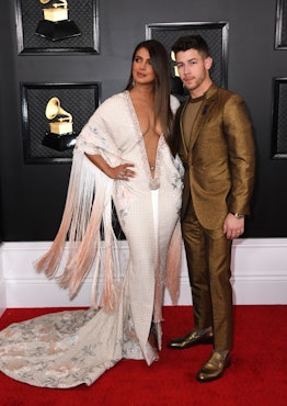 Priyanka Chopra wears a white embellished gown and stands next to husband Nick Jonas on the 2020 Gra...