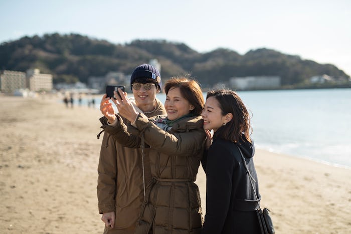 husband, wife, and mother-in-law on a beach taking a selfie