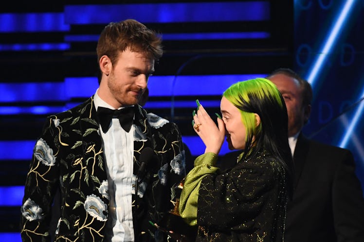 Billie Eilish stands on stage with her brother while accepting a Grammy award.