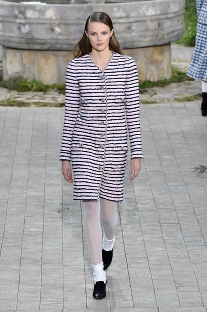 A model in a black-white striped coat, white tights and socks, and black shoes as a Spring 2020 tren...