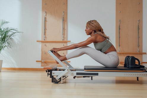 A person prepares to do Pilates exercises on a reformer. Pilates has a lot of potential mental healt...