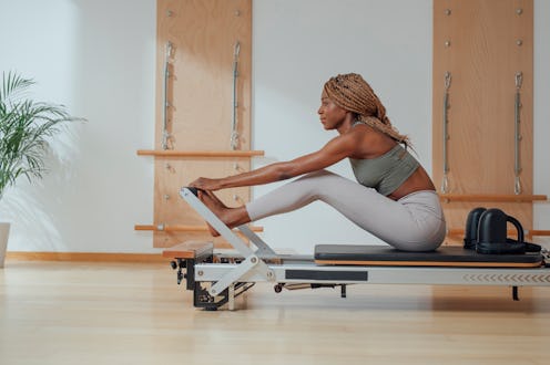 A person prepares to do Pilates exercises on a reformer. Pilates has a lot of potential mental healt...