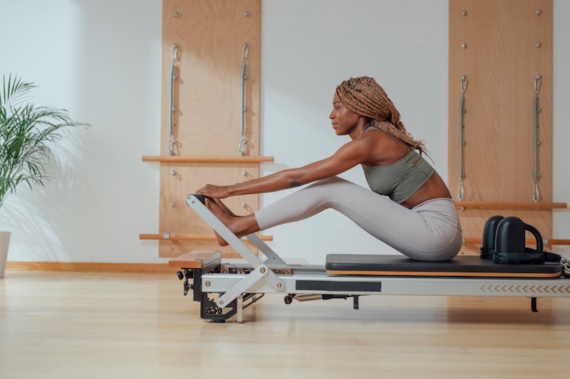 A person prepares to do Pilates exercises on a reformer. Pilates has a lot of potential mental healt...