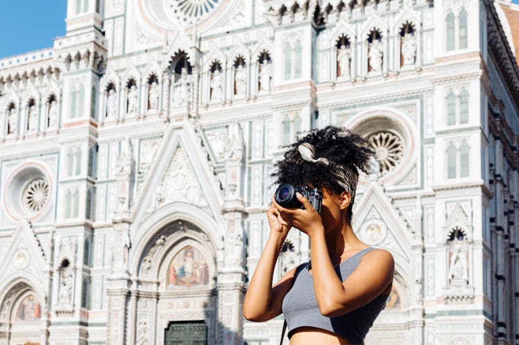 A young woman takes a picture on her digital camera while standing near the Duomo in Florence, Italy...