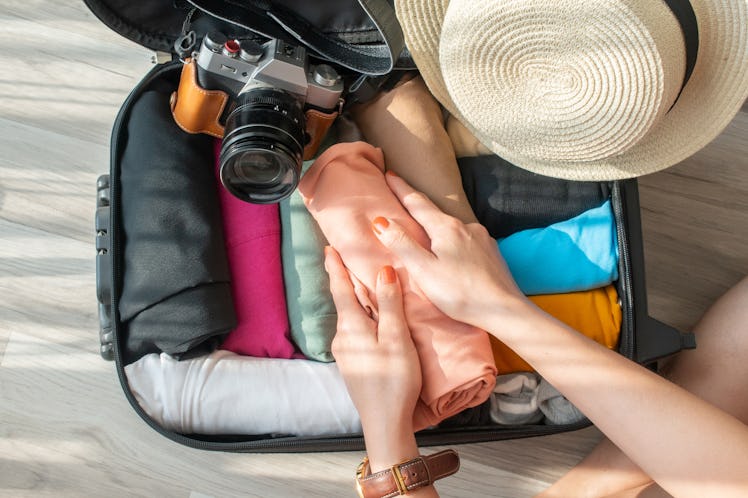 A woman rolls her clothes to better fit them into a carry-on bag before a trip.