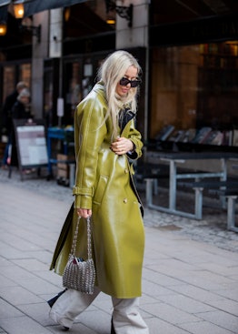 A woman in a leather olive trench coat, chain bag and beige trousers at the Copenhagen Fashion Week