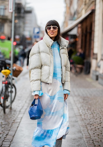 A woman in a white-blue dress, white puffer jacket and a blue bag at the Copenhagen Fashion Week