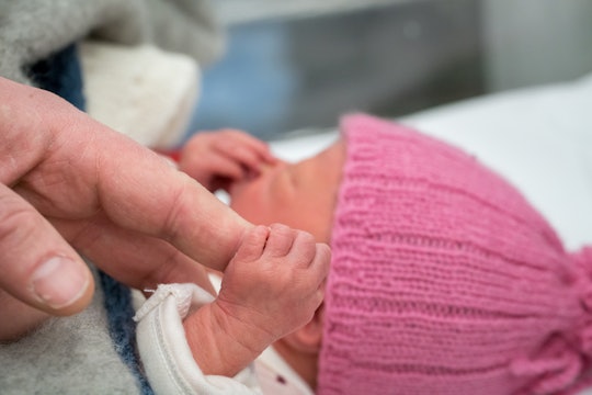 a newborn gripping an adult's finger