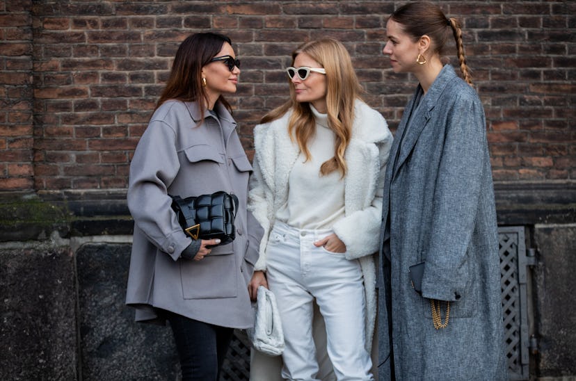 A woman in a grey skirt and black pants, a woman in all-white, and a woman in a grey coat at the Cop...